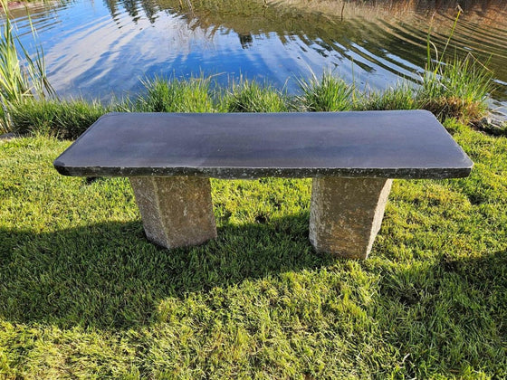 Natural stone bench used as garden seating beside a pond