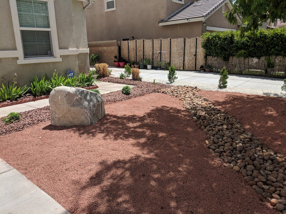 Front yard combining several landscape rock types: decomposed granite, a river-rock dry creek, and a boulder