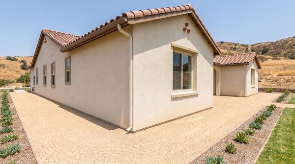 Decomposed granite raked clean along the foundation of a California home, with succulent planting set back from the wall