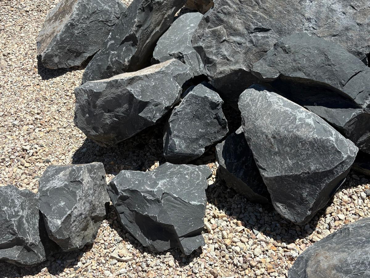 Angular Black Hawk landscape boulders in dark charcoal shale on a gravel yard surface