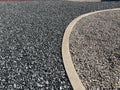 Black n Silver Rock 1 inch meeting tan gravel along a curved concrete landscape curb
