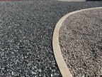 Black n Silver Rock 1 inch meeting tan gravel along a curved concrete landscape curb