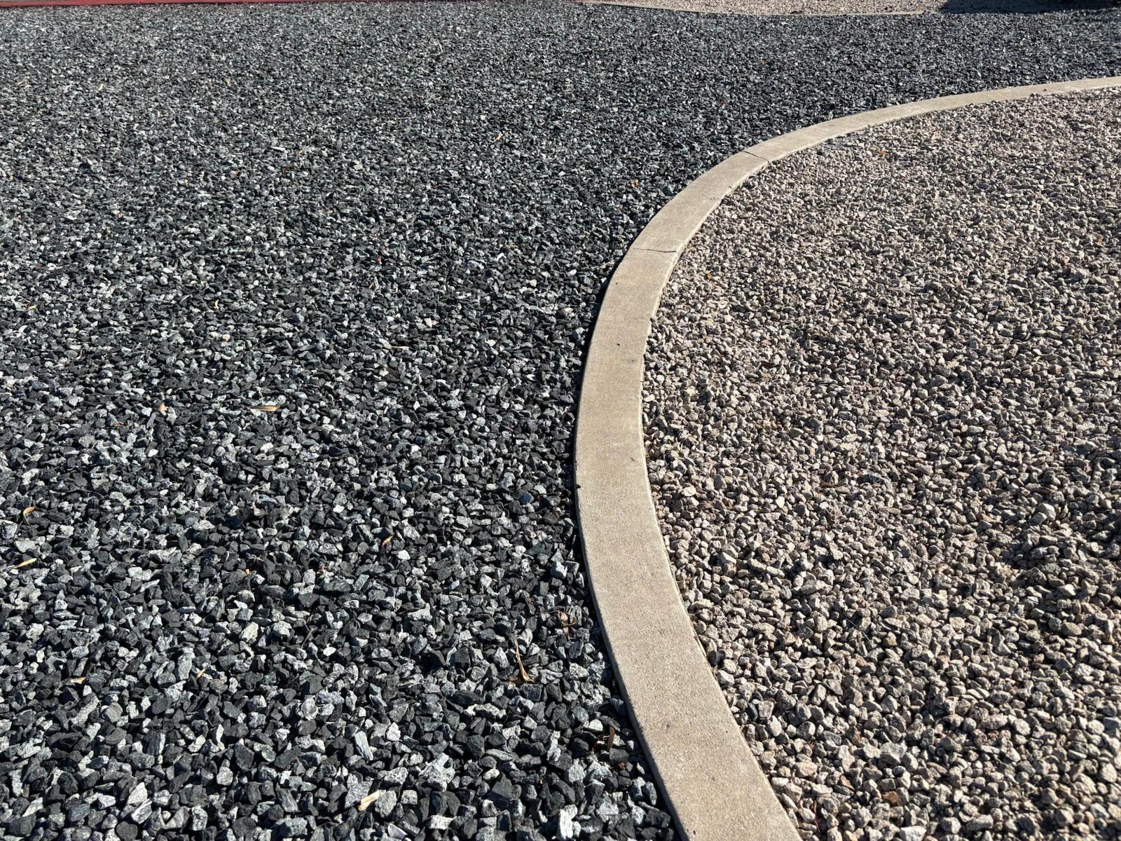 Black n Silver Rock 1 inch meeting tan gravel along a curved concrete landscape curb