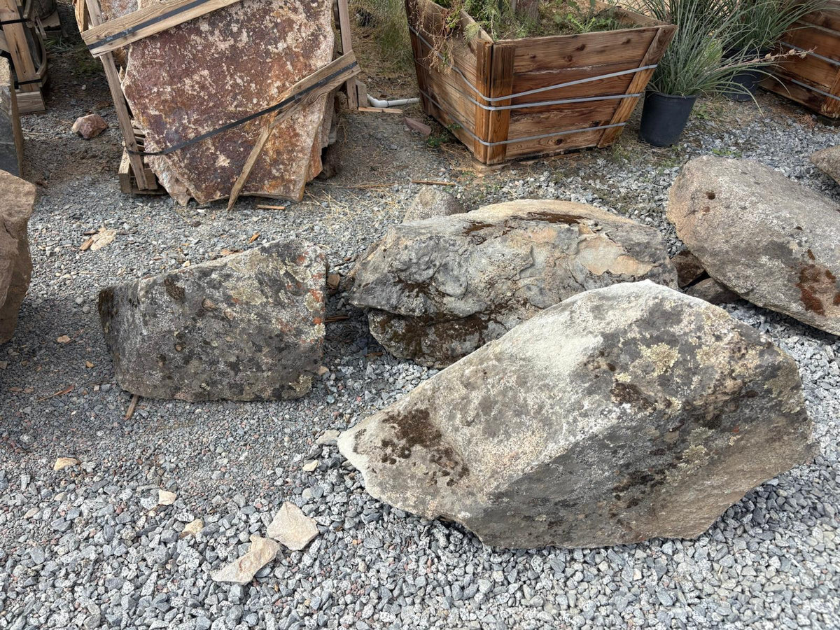 Weathered granite moss rock boulders laid out on gravel